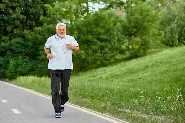 Premium Photo | Old man running on modern city park's racetrack.